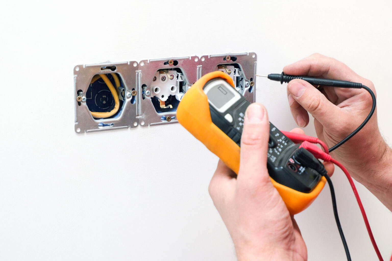 Elektryk mierzy multimetrem napięcie w gnieździe ściennym