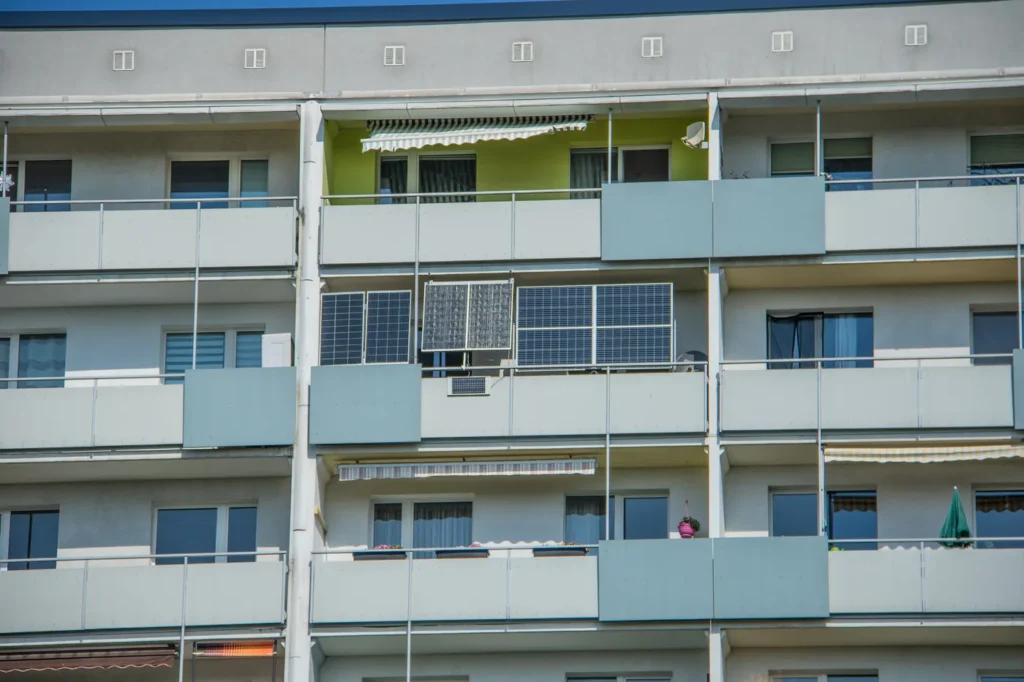 Fotowoltaika balkonowa – czy to legalne, ile daje i ile kosztuje Panele fotowoltaiczne zawieszone na balustradach balkonów bloku z wielkiej płyty