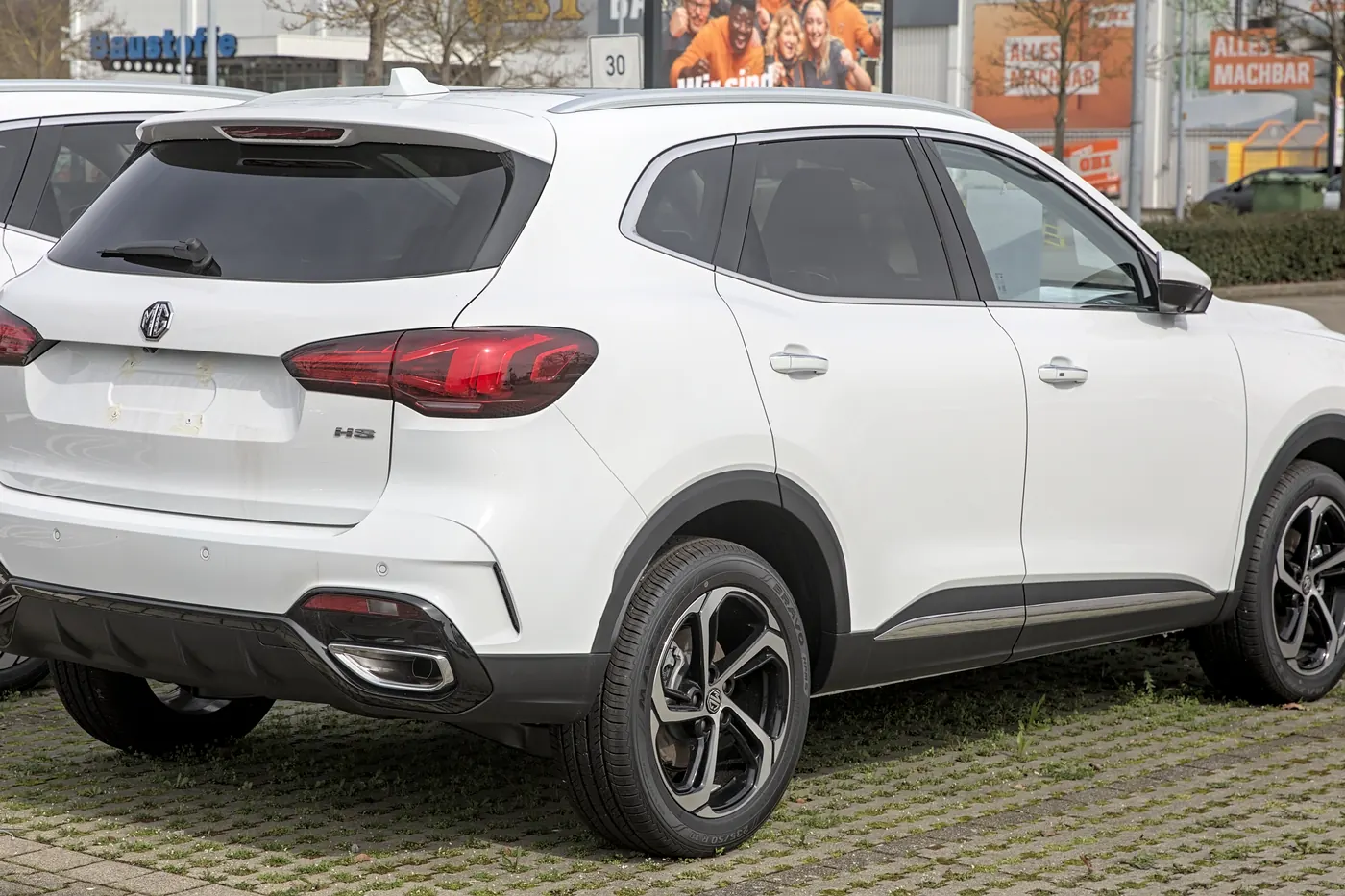 Biały MG HS – kompaktowy SUV marki MG sfotografowany od tyłu na placu dealera