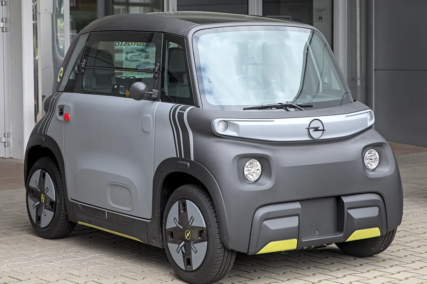 Szary Opel Rocks-e z żółtymi akcentami stoi przed salonem