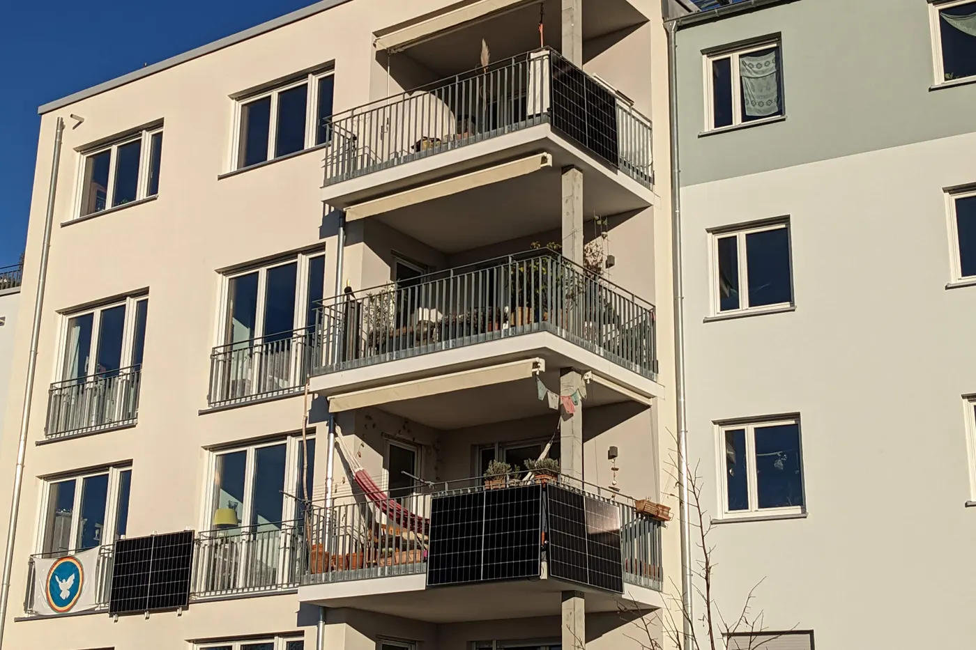 Panele fotowoltaiczne zawieszone pionowo na balustradach balkonów w bloku mieszkalnym